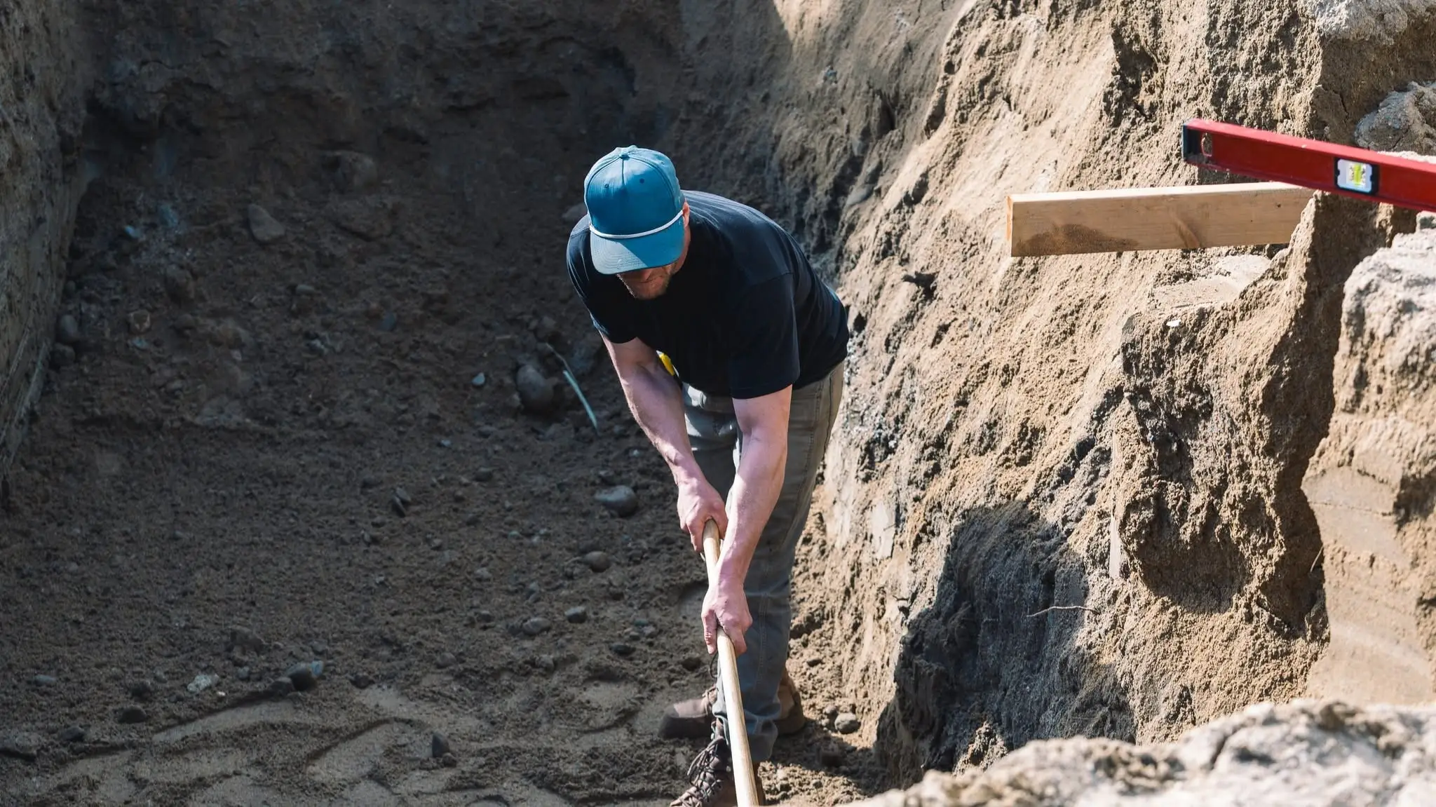 A crew member digging out an excavation for a Rega client