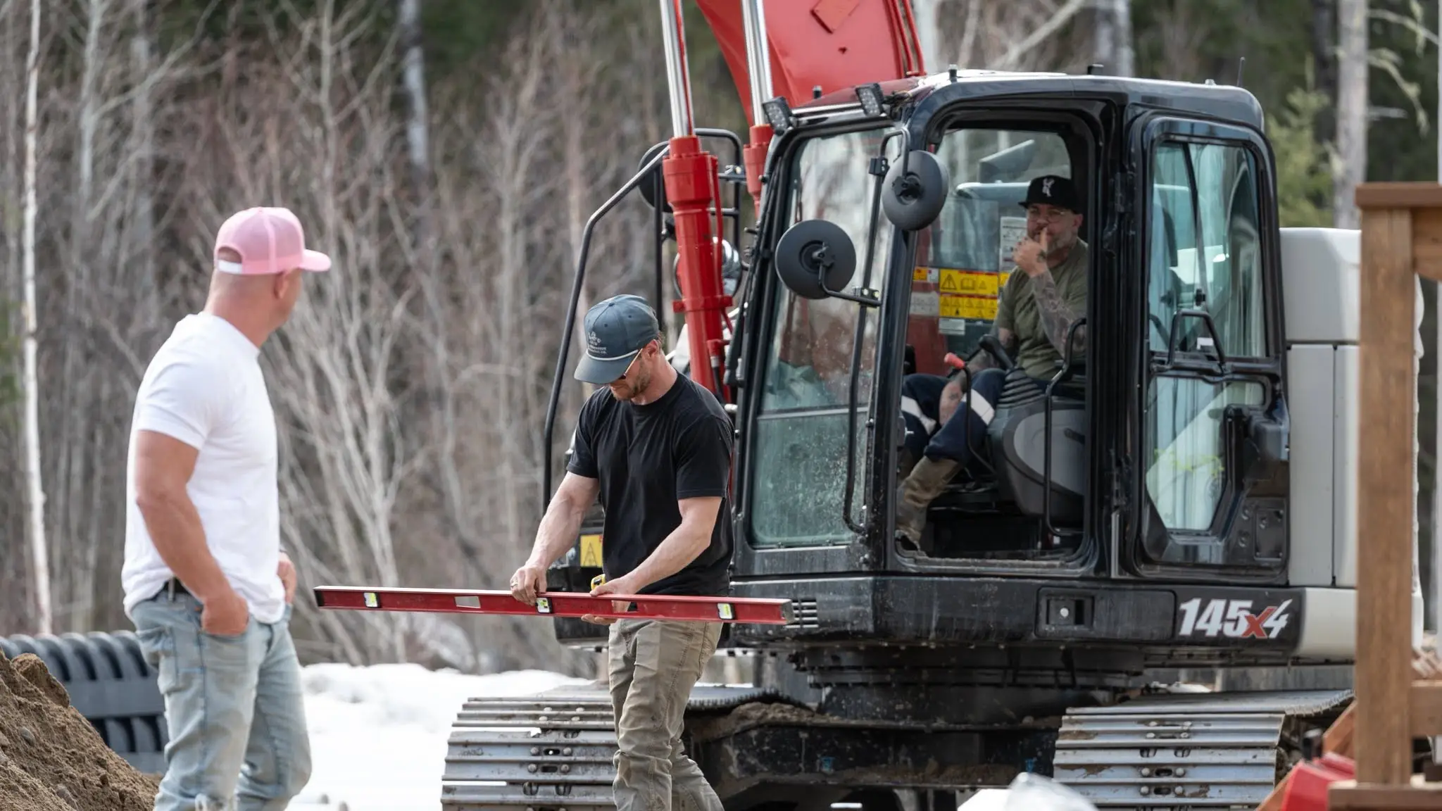 Three tradespeople working on a site for a Rega client, one levelling beside an excavator