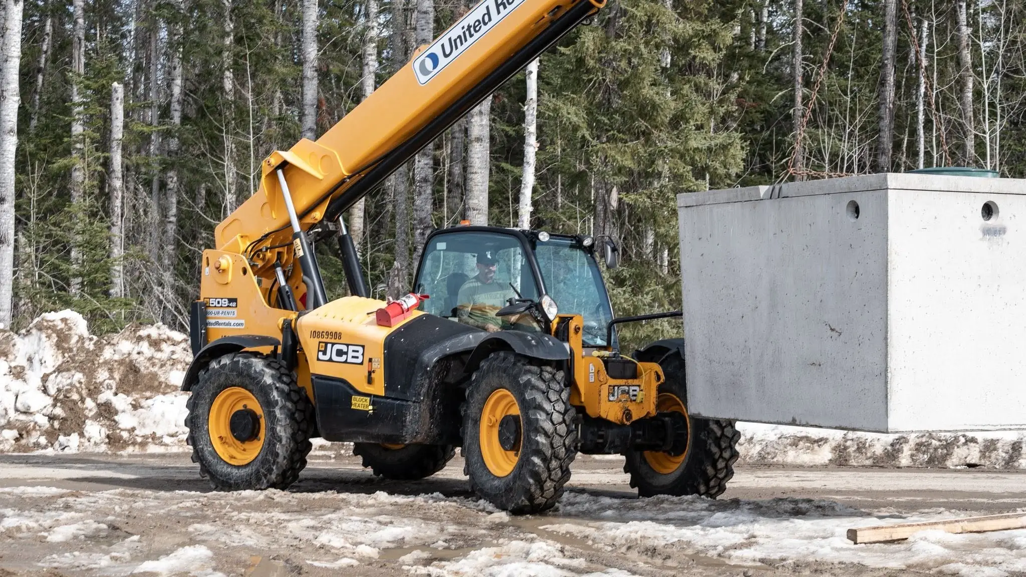 An operator setting a septic tank from the cab of an excavator